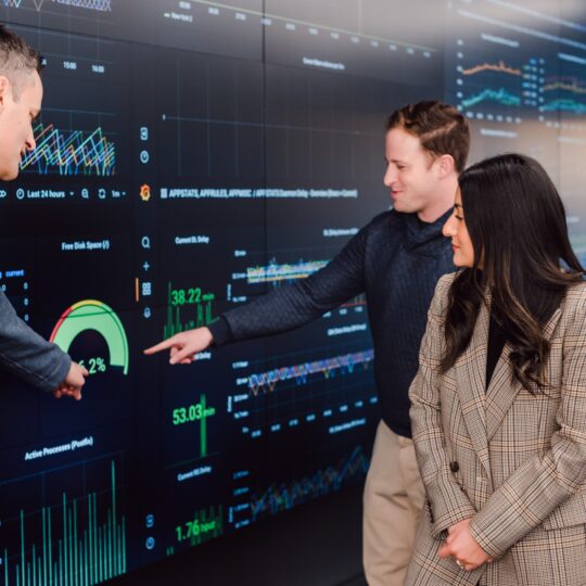 four-index-employees-gathered-around-data-filled-wall