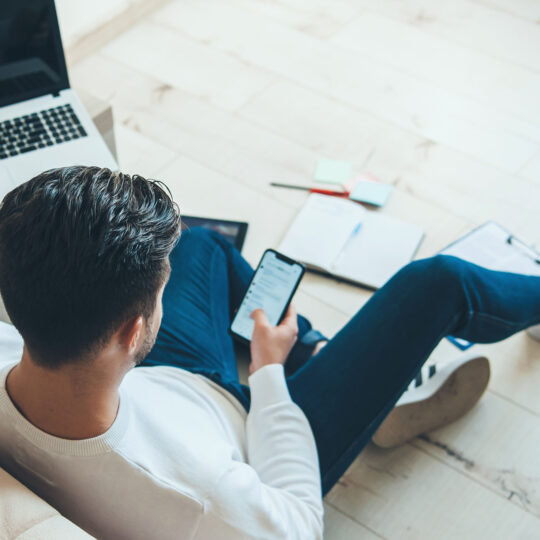 person sitting on the floor with a computer and aphone